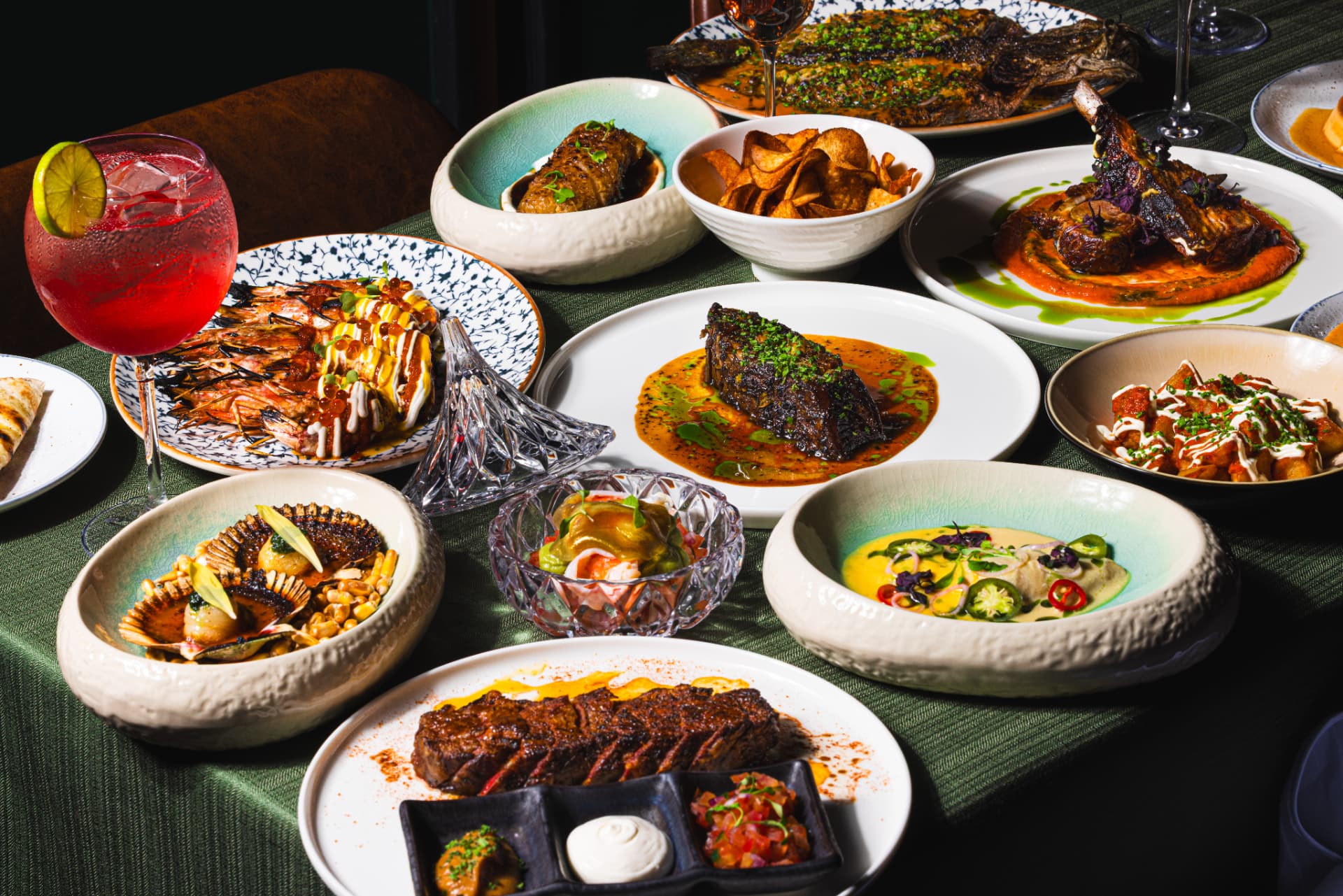 A full table spread of dry-aged meat, seafood and cocktails at The Margin Singapore